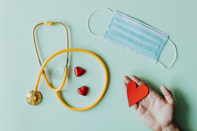 medical equipment with persons hand holding paper heart