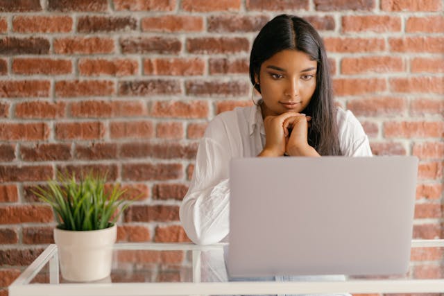 women sat at laptop thinking